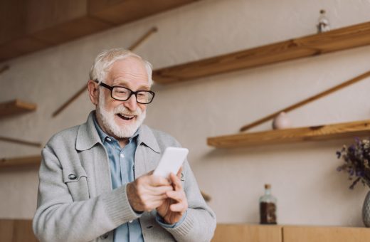 happy senior man using smartphone and looking at camera